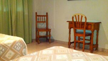 Una habitación con una cama, una silla, un escritorio, un televisor y un cuadro en la pared.