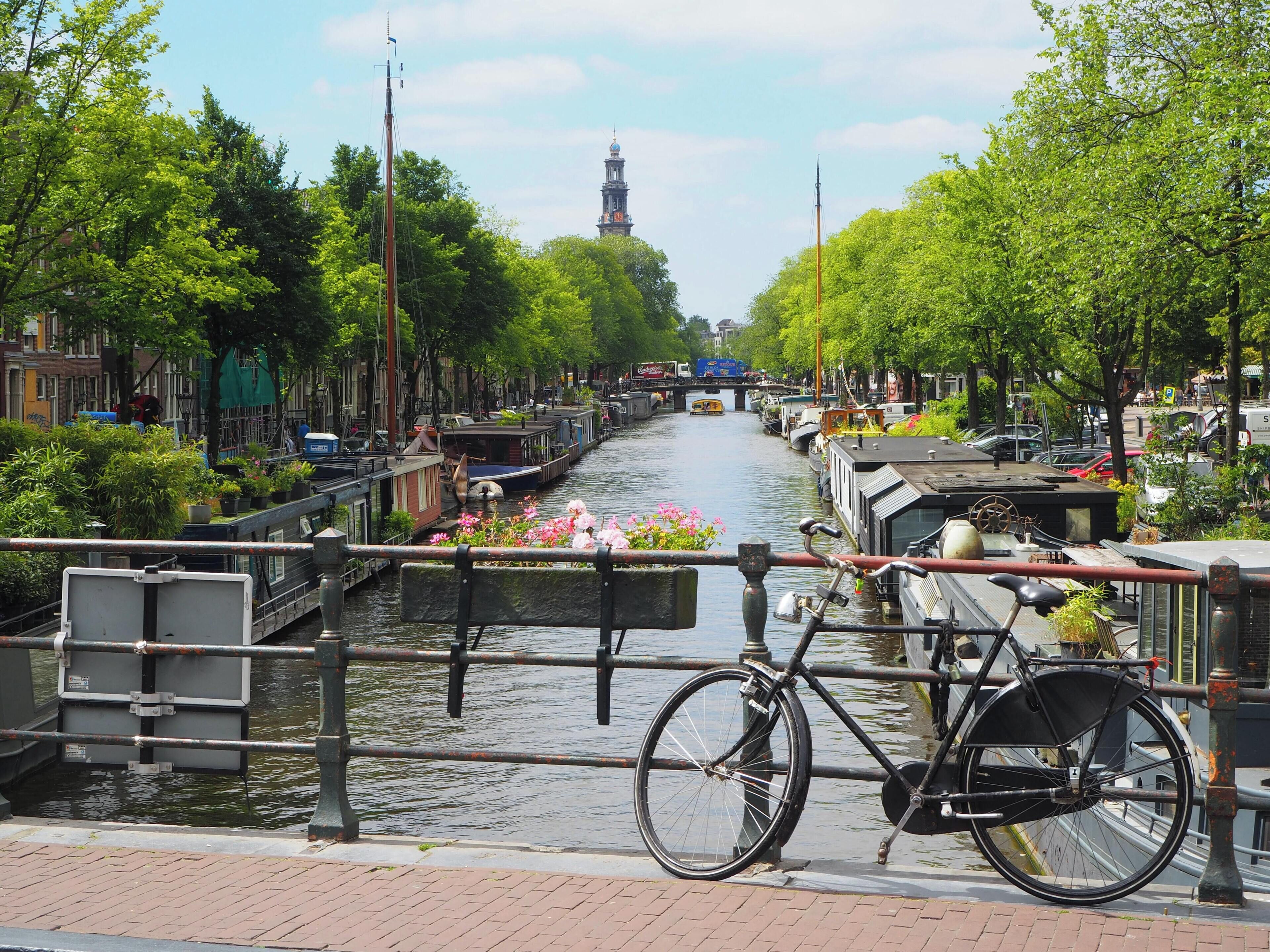 A canal with boats, a bicycle, and a bridge.