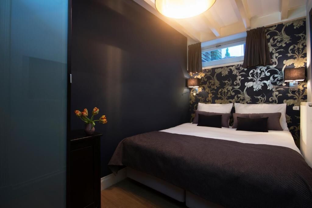 A bedroom with a large bed, dark walls, and a window with curtains.