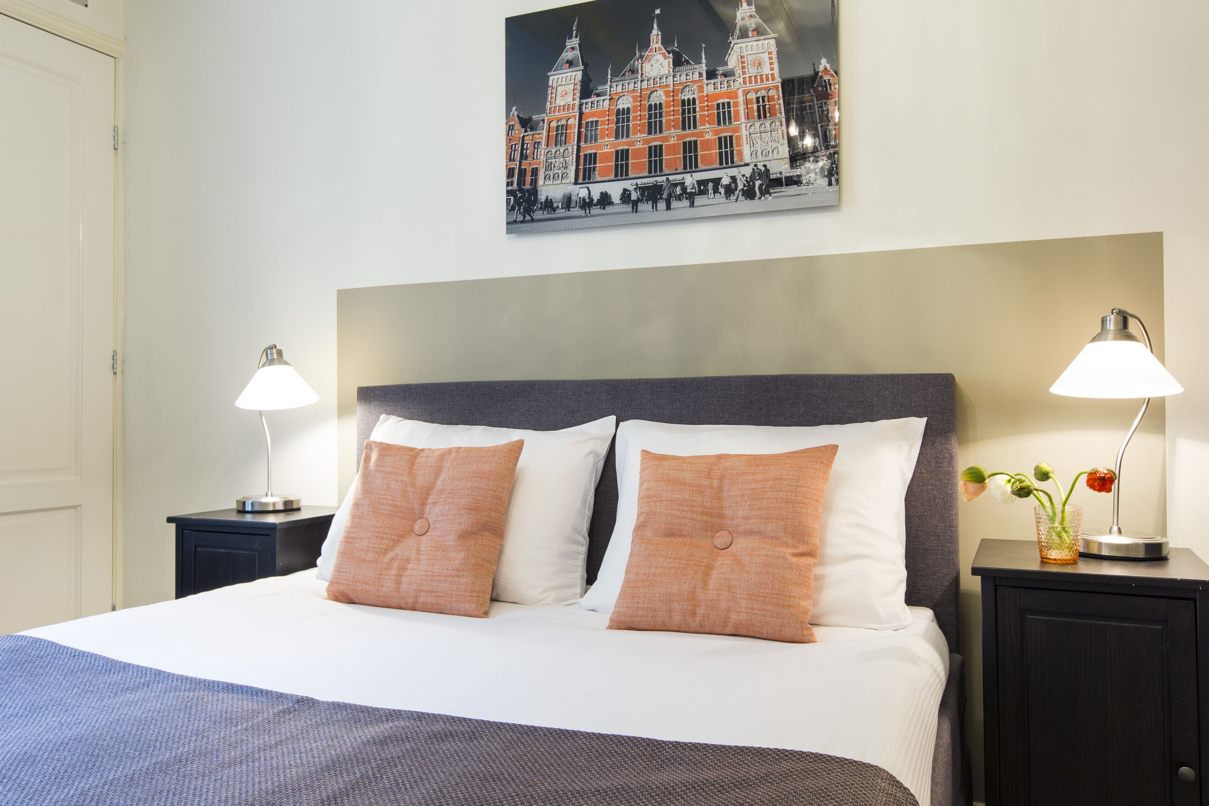 A neatly made bed with two pillows, a headboard, and two bedside tables with lamps.