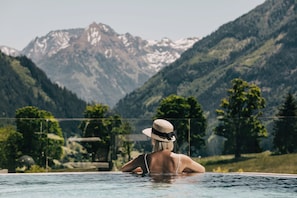 A person in a swimming pool with a mountain view in the background.