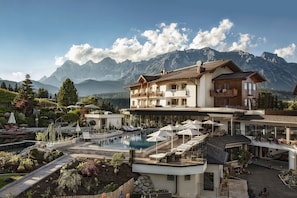 A resort with a swimming pool, lounge chairs, and mountain views.