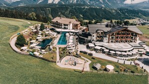 A hotel with a pool, outdoor seating, and mountain views.
