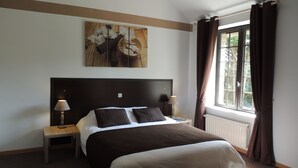 Ein Hotelzimmer mit einem großen Bett, zwei Nachttischen mit Lampen, einem Fenster mit Vorhängen und einem Wandbild.