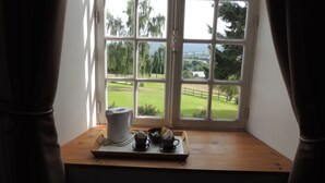 Ein Fenster mit Blick auf eine grüne Landschaft und ein Haus.