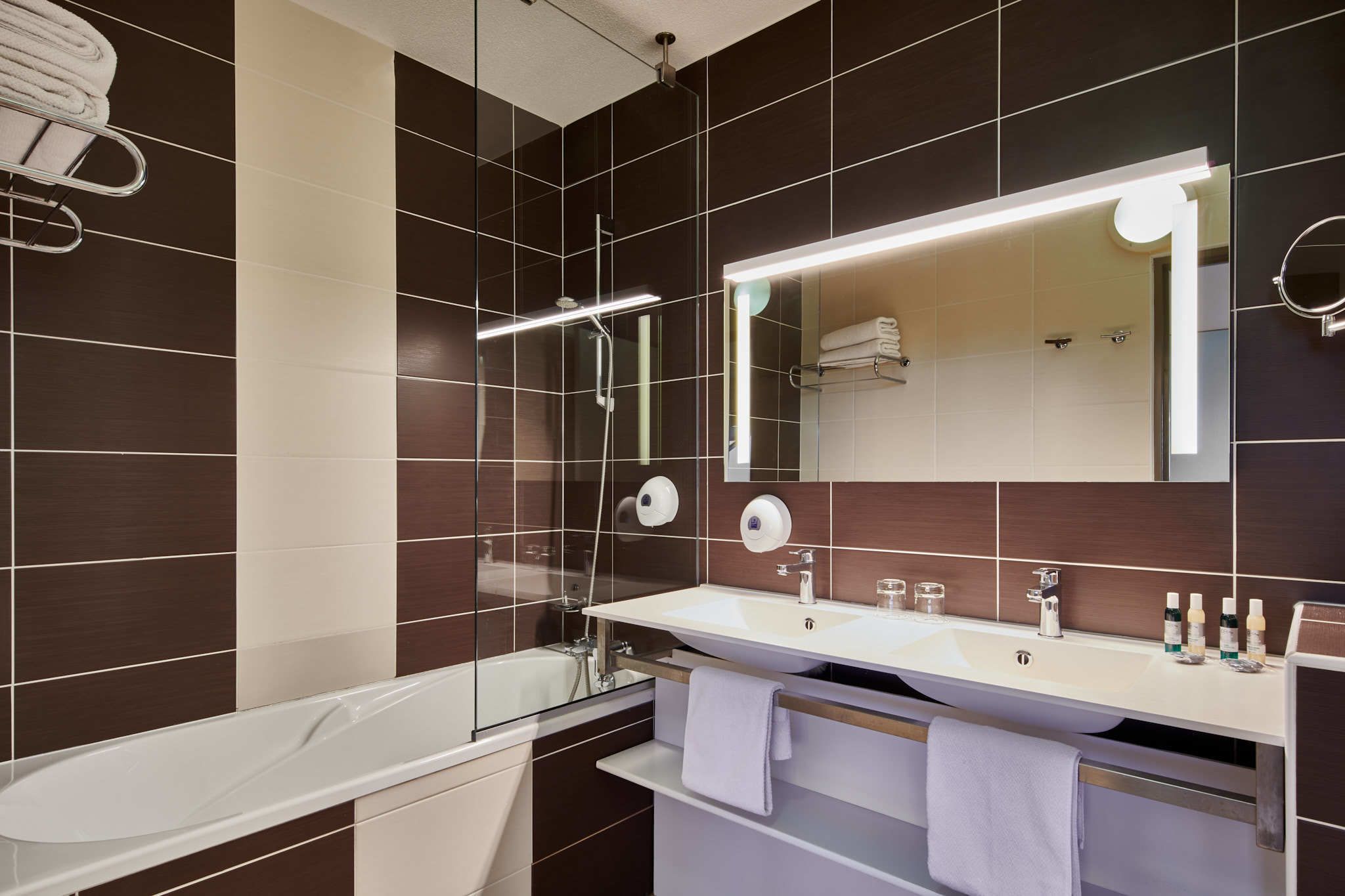 A modern bathroom with a glass-enclosed shower, a white sink, and a large mirror.