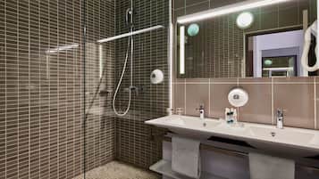Un bagno moderno con cabina doccia in vetro, uno specchio grande e un mobile lavabo con due lavandini.