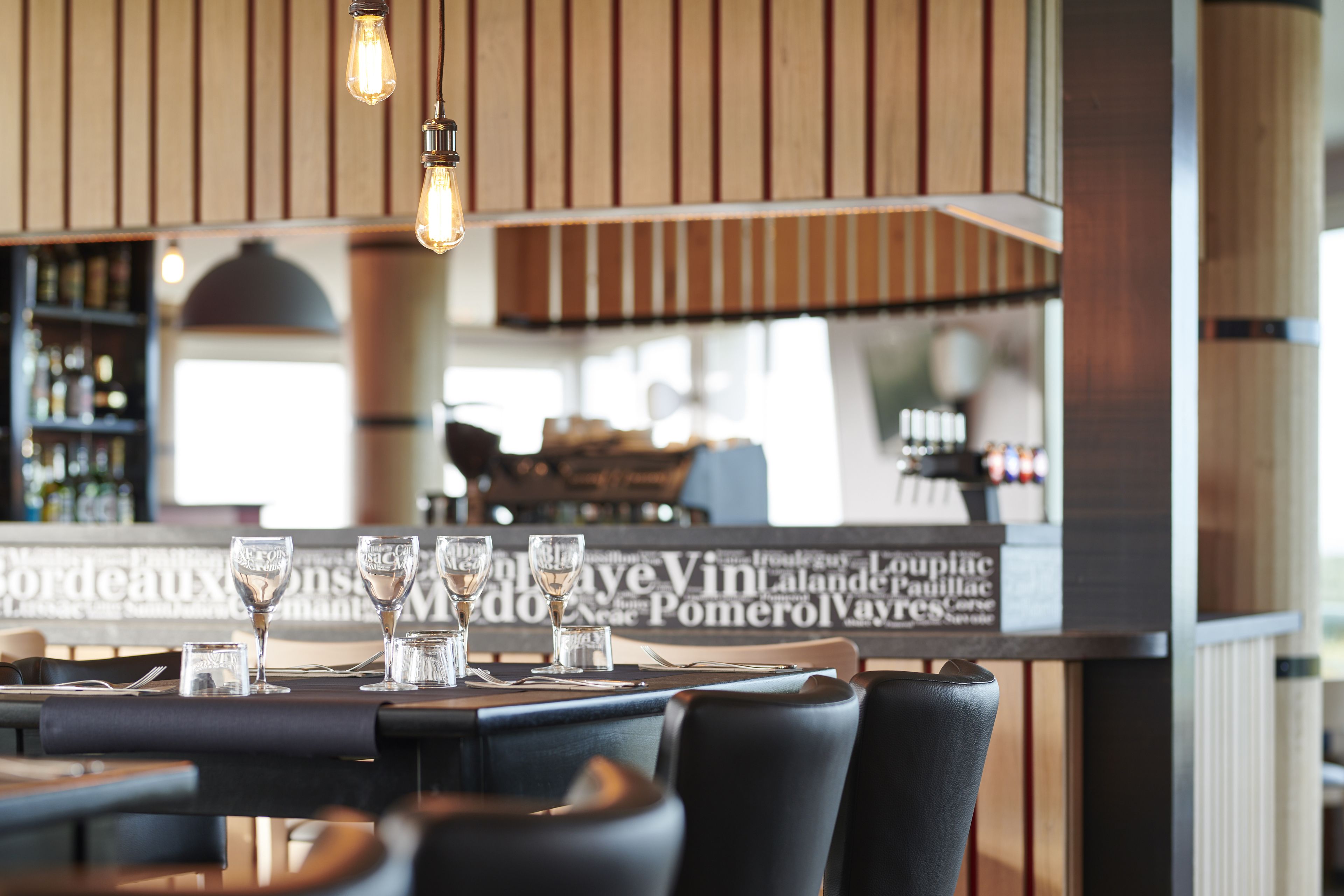A restaurant interior with a bar area, wooden paneling, and a menu board.