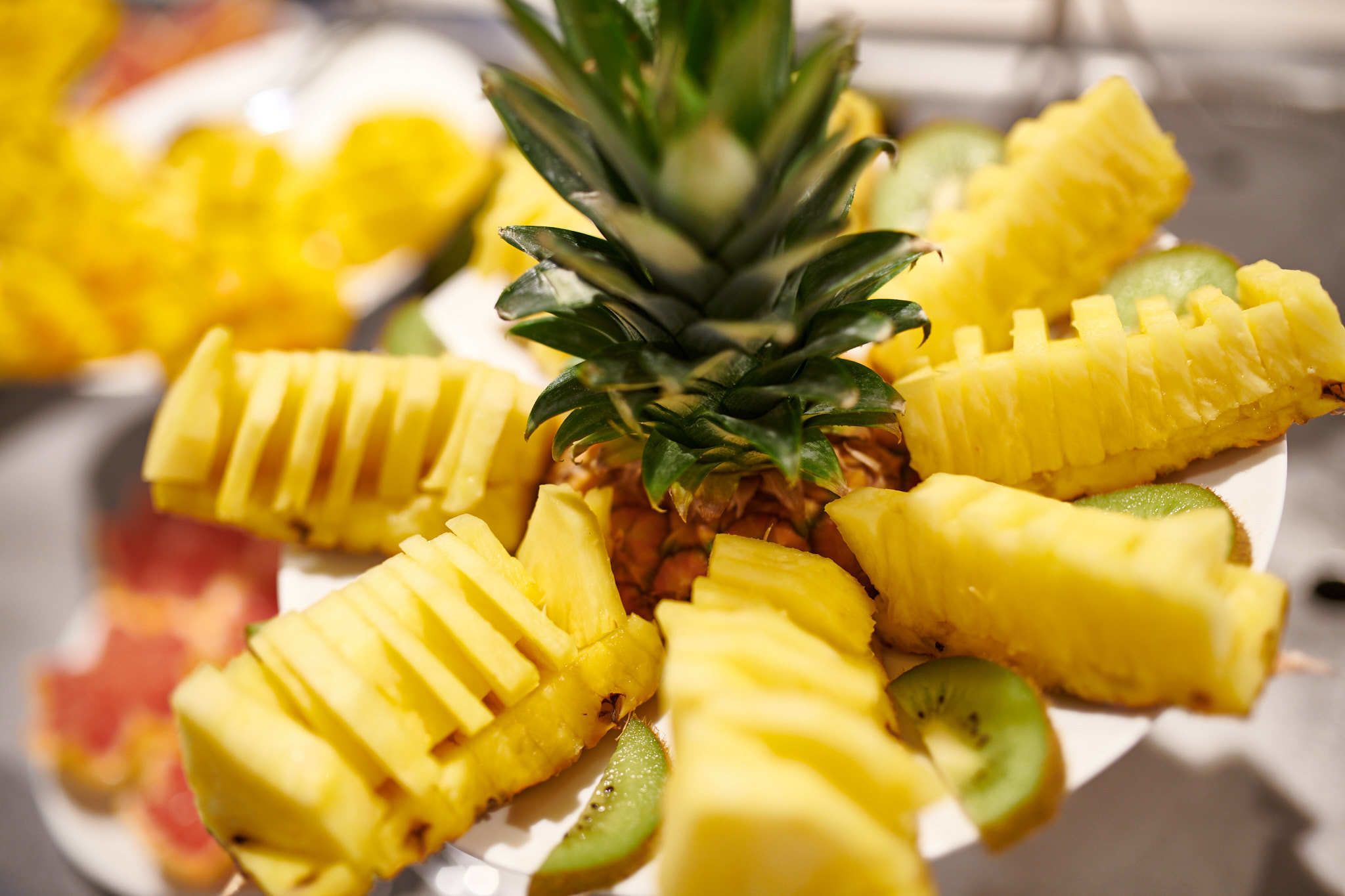A plate of sliced pineapple and kiwi arranged on a white plate.