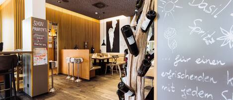 A modern interior with wooden panel walls, a reception desk, and a wine rack with bottles.