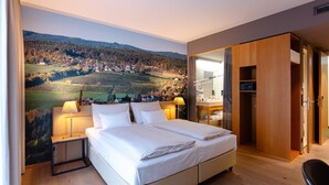 Un dormitorio con una cama grande, lámparas de noche, un armario de madera y un mural de un viñedo en la pared.