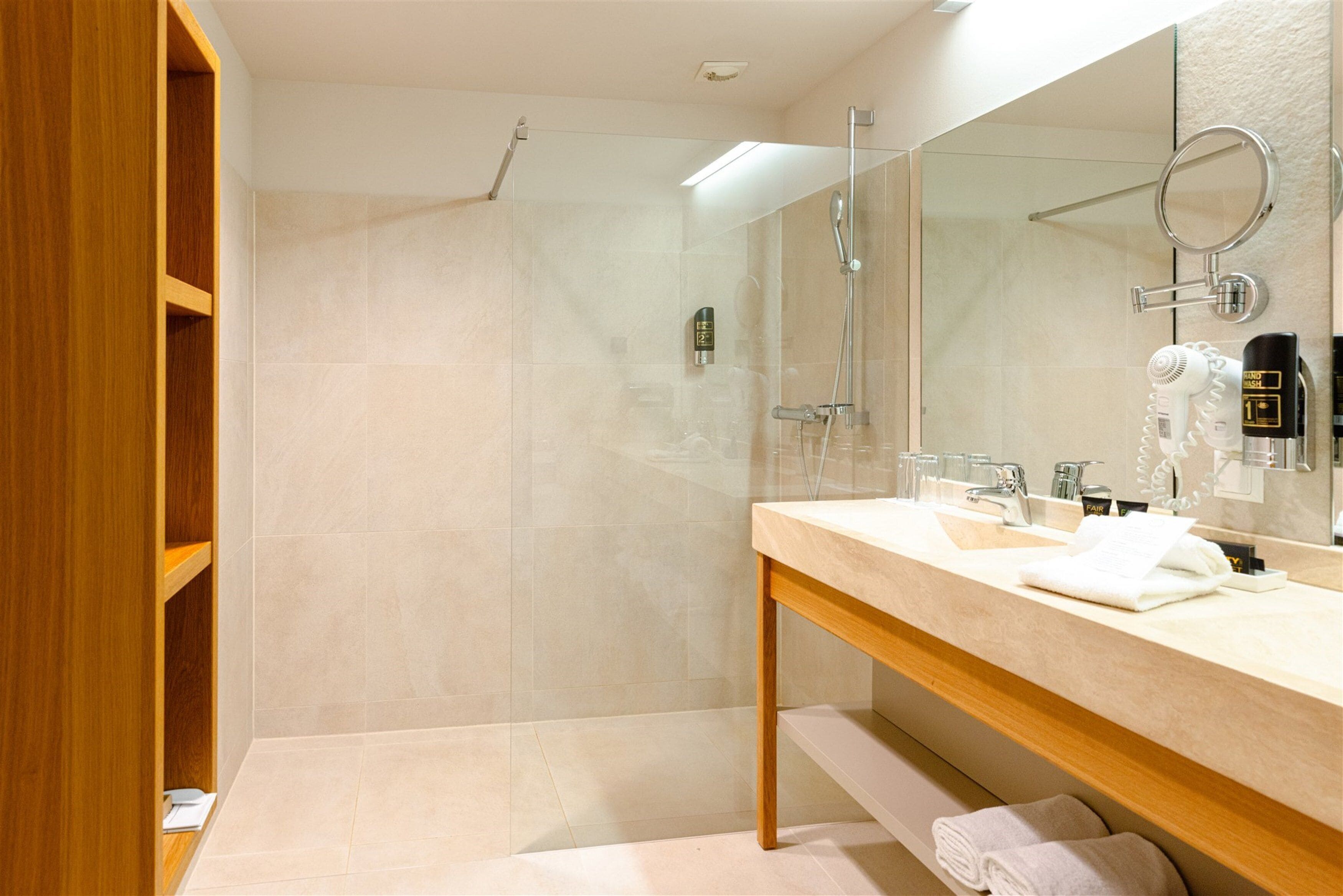 Une salle de bain moderne avec une douche à parois de verre, un meuble-lavabo en bois avec un miroir et un porte-serviettes.