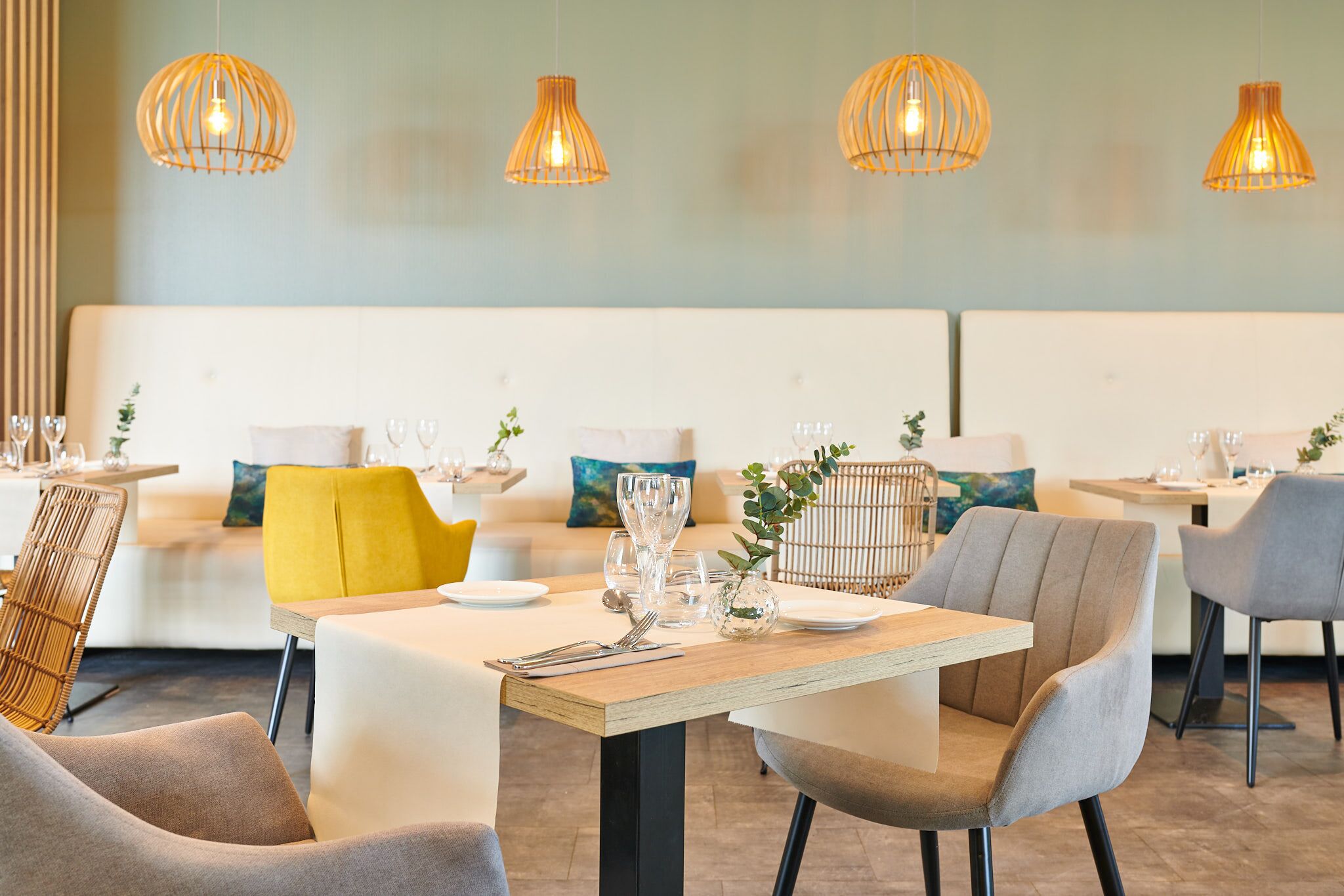 A modern dining area with round tables, cushioned chairs, and pendant lighting.