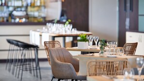 A restaurant with tables set for dining, chairs, and a bar area in the background. - Hôtel Les Terrasses d'Atlanthal (Anglet)