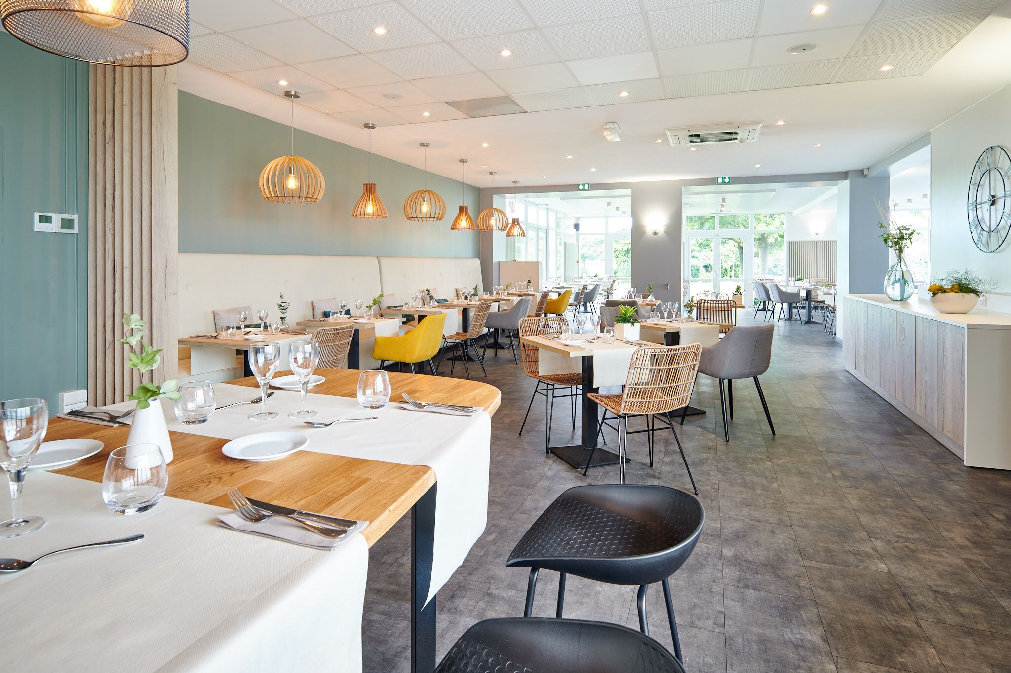 Een modern restaurant met meerdere eettafels, stoelen en hanglampen.