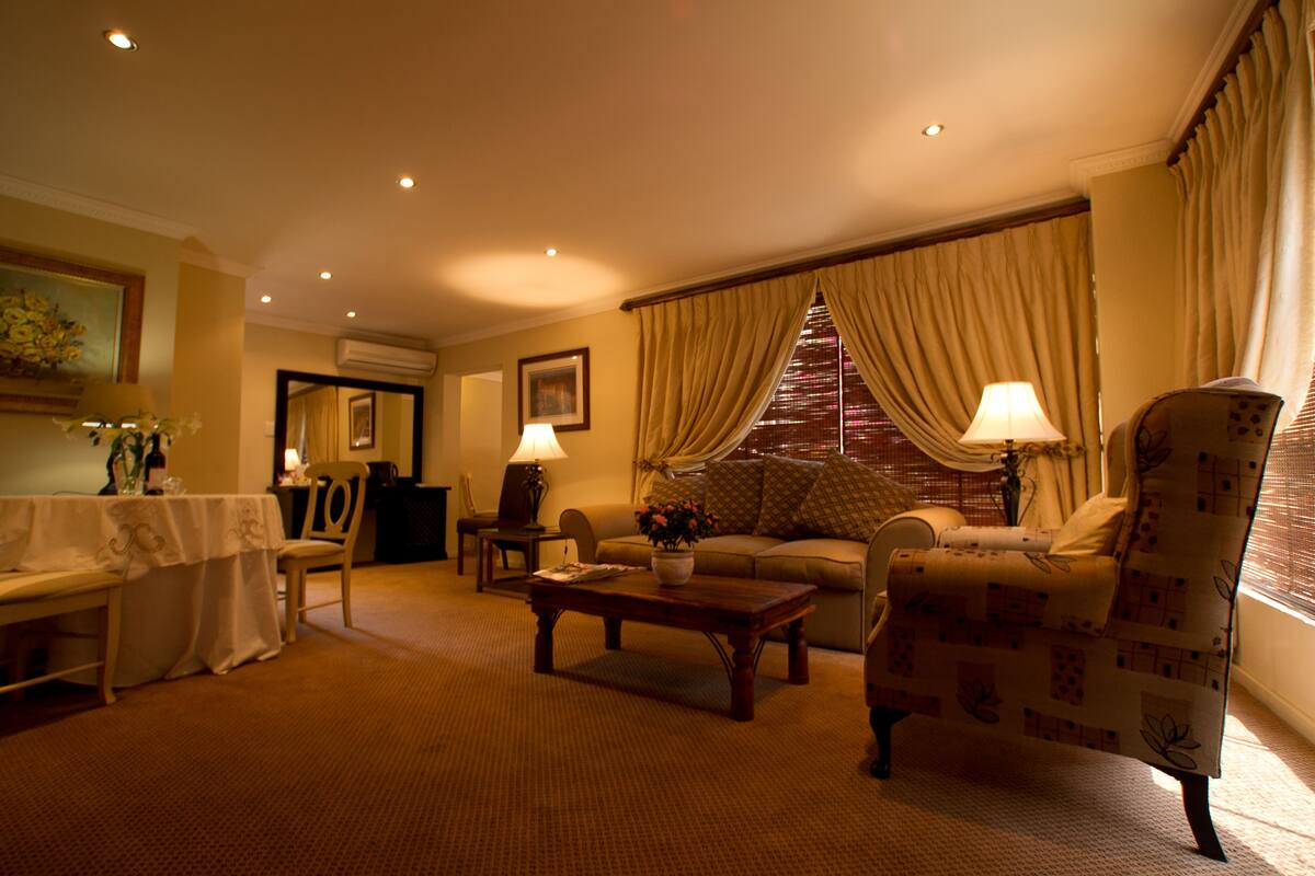 Un salon bien éclairé, comprenant un canapé, un fauteuil, une table basse et un coin repas avec une table et des chaises.