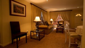 A hotel room with a sofa, a chair, a table, and a lamp. - Little Tuscany Boutique Hotel (Sandton)