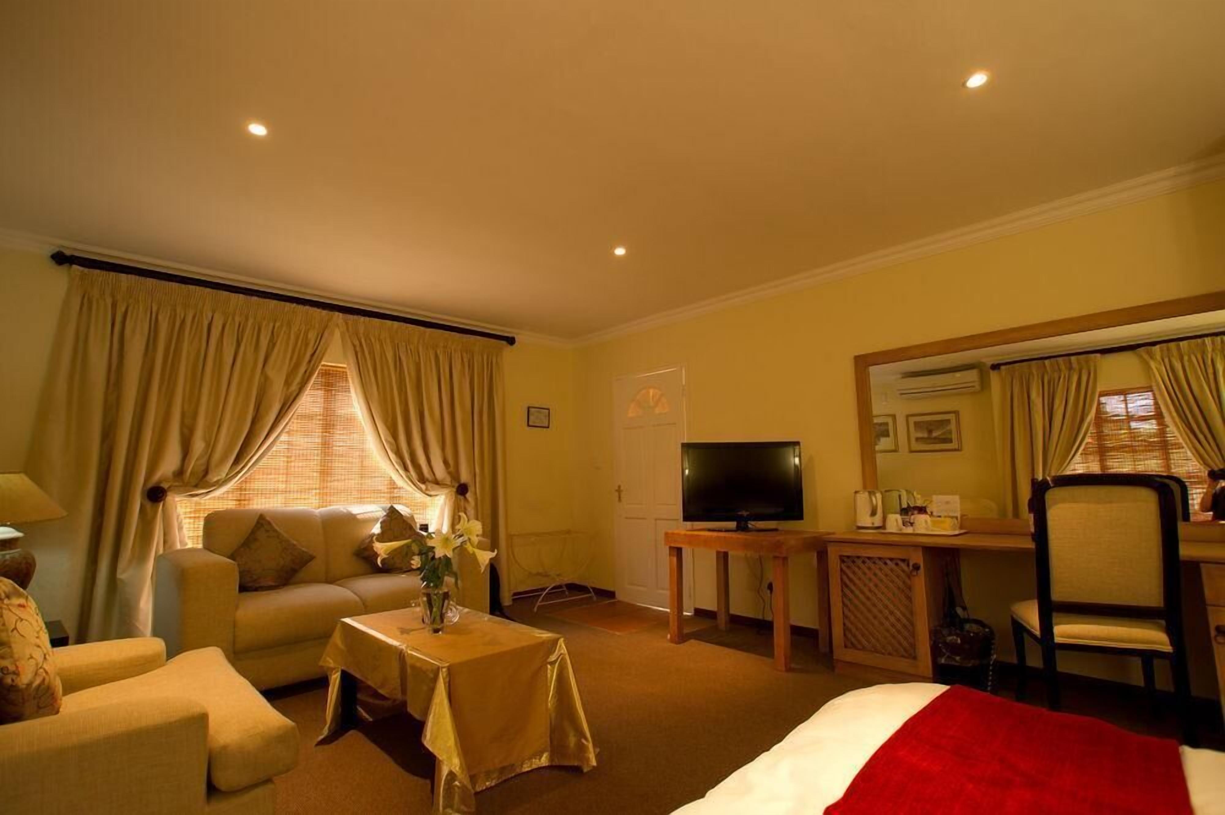 A hotel room with a bed, a sofa, a TV, a desk, and a chair.