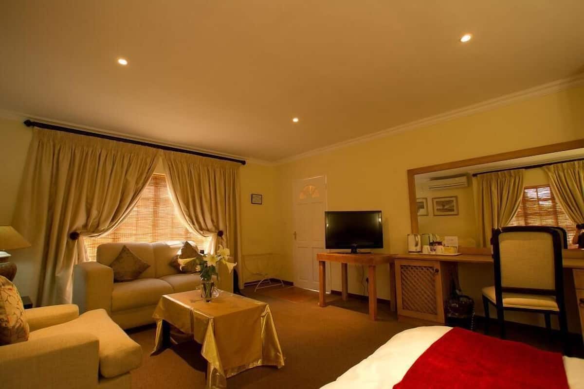 Une chambre d’hôtel avec un lit, un canapé, une télévision, un bureau et une chaise.