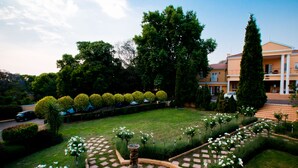 A well-maintained garden with a fountain, neatly trimmed hedges, and a large building in the background. - Little Tuscany Boutique Hotel (Sandton)