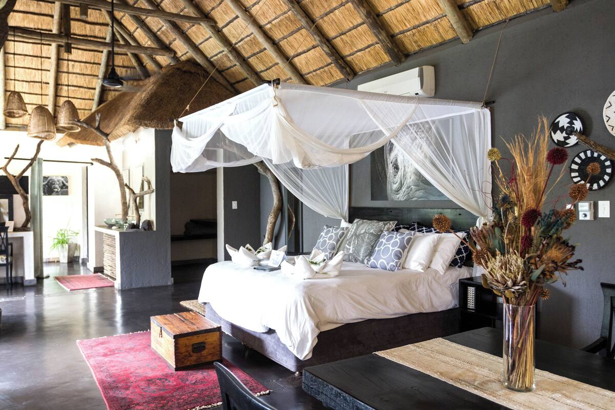 A spacious bedroom with a large bed, a canopy, and a vase with dried flowers.