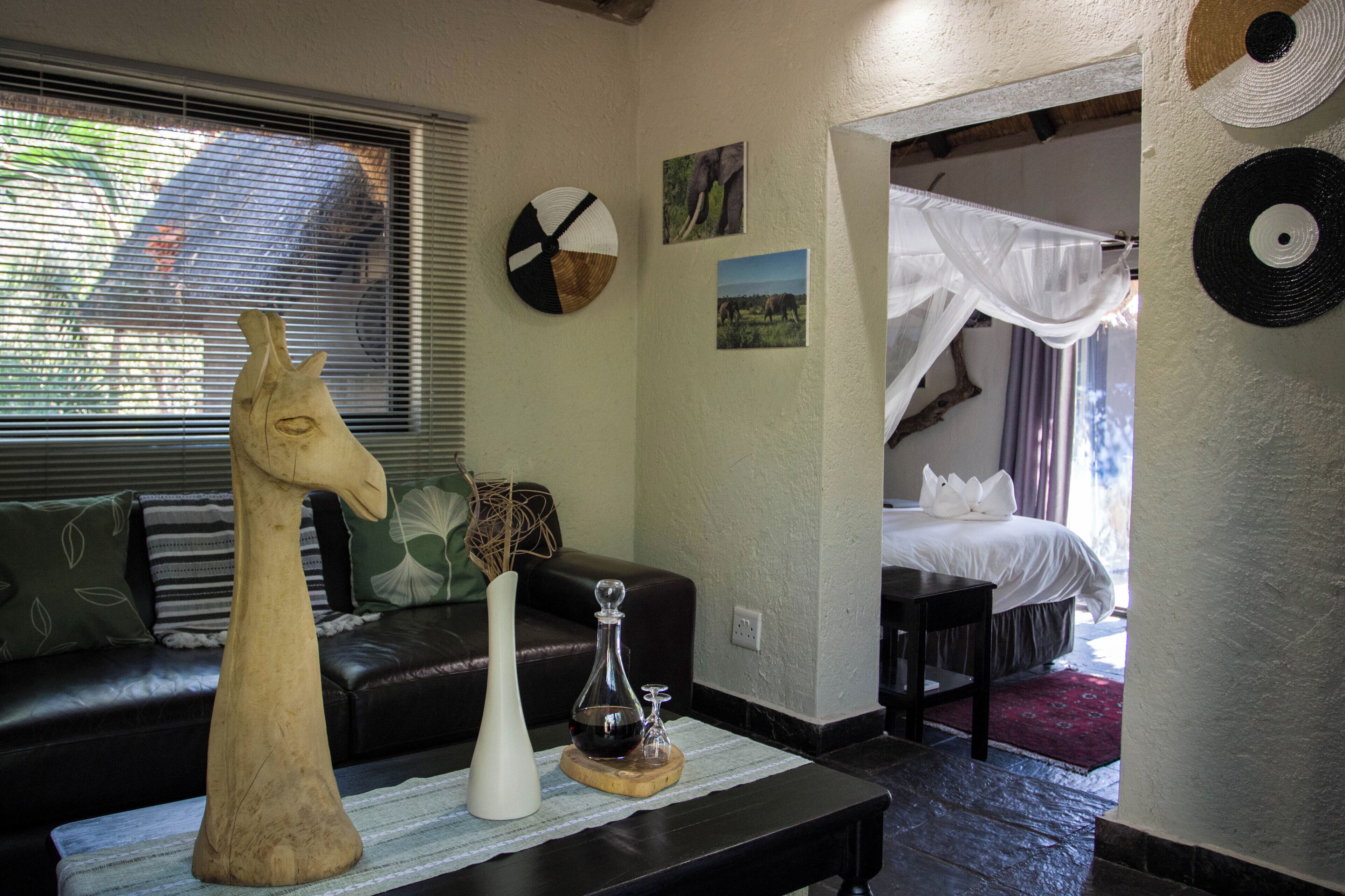 A room with a bed, a wooden horse sculpture, a vase, and a picture of elephants on the wall.