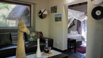 A room with a bed, a wooden horse sculpture, a vase, and a picture of elephants on the wall.