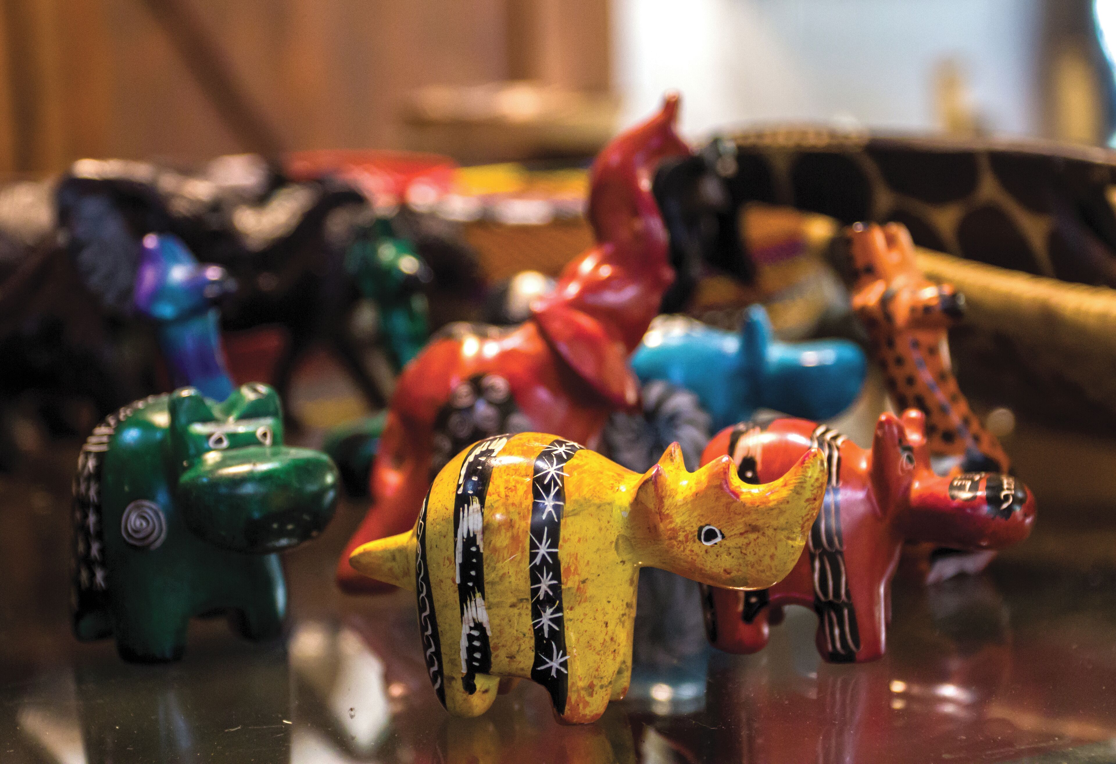 A collection of colorful ceramic animal figurines on a reflective surface.