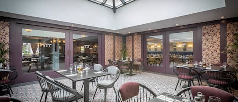Un restaurante con techo alto, piso estampado y mobiliario moderno.