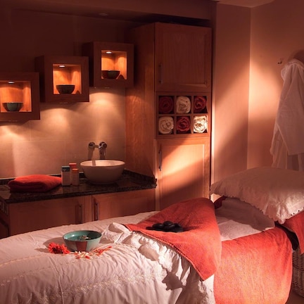 A bedroom with a bed, a bedside table, a mirror, and a wooden cabinet with shelves.