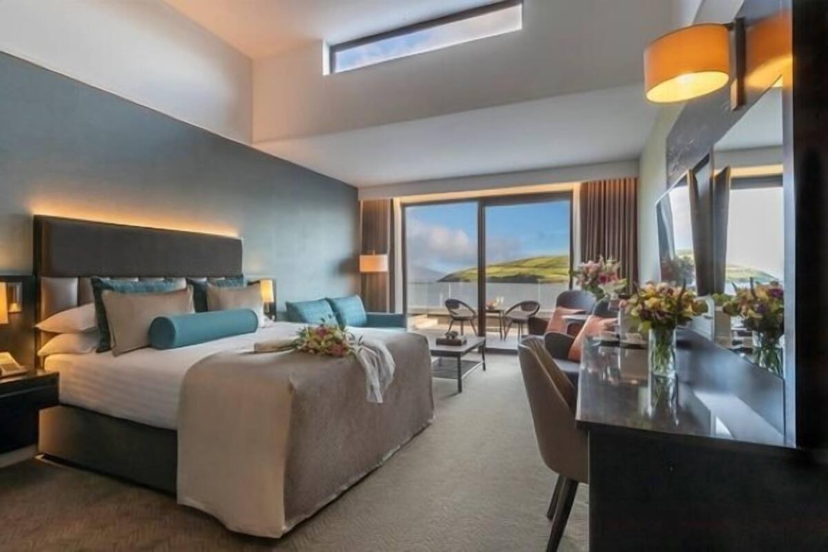 A modern hotel room with a large bed, a desk, and a view of the outdoors.
