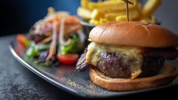 A burger with a toothpick on top, accompanied by a side of fries.