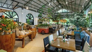 An indoor plant shop with wooden tables, chairs, and various potted plants. - Nurture Wellness Village (Tagaytay)