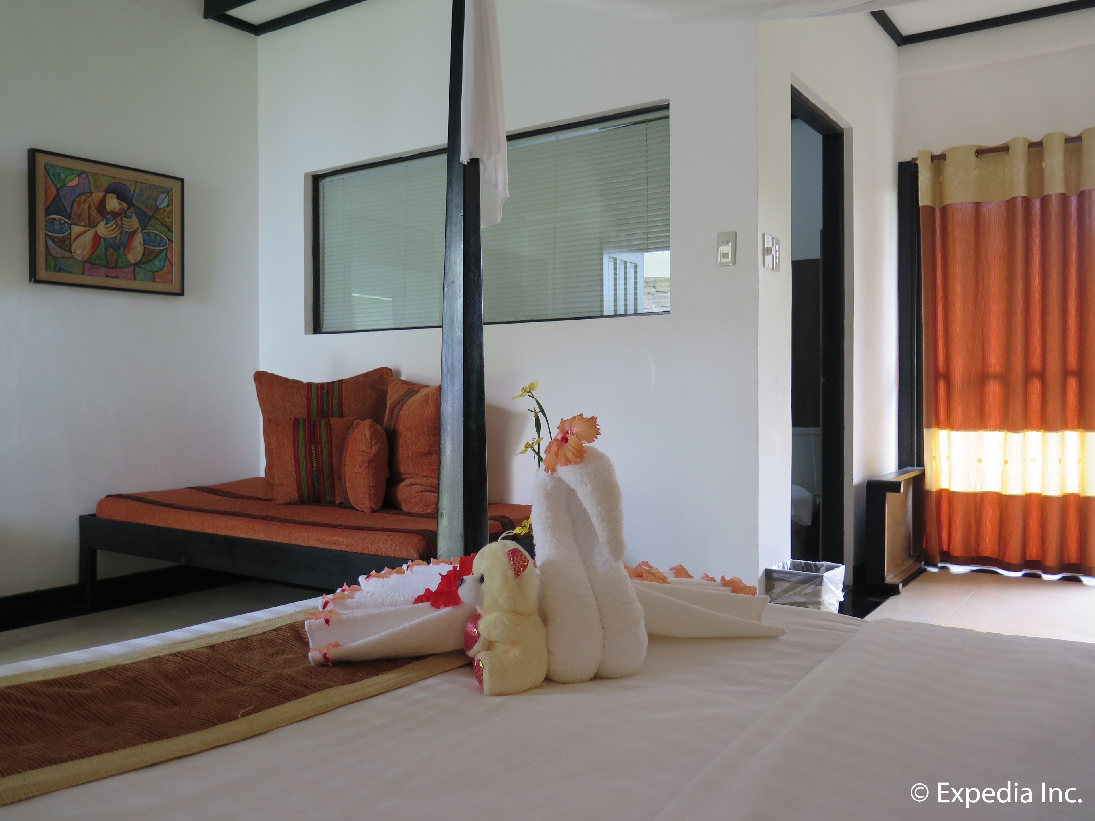 Une chambre moderne avec un lit, un canapé, un tableau et une fenêtre avec des rideaux.