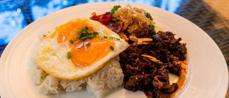 A plate of food with rice, a fried egg, and a meat dish.