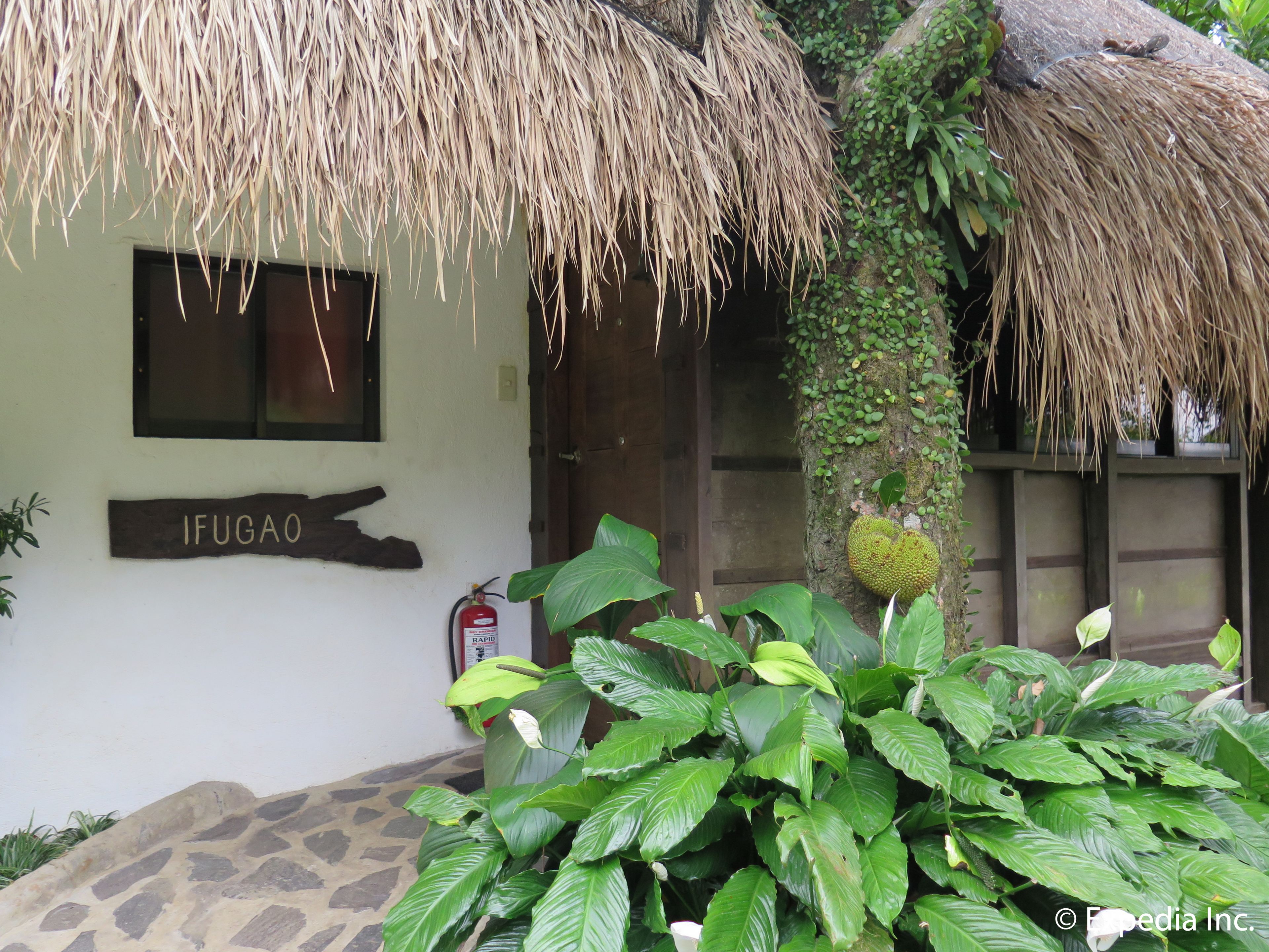 A building with a sign reading "IFUGAO," a thatched roof, and a fire extinguisher mounted on the wall.