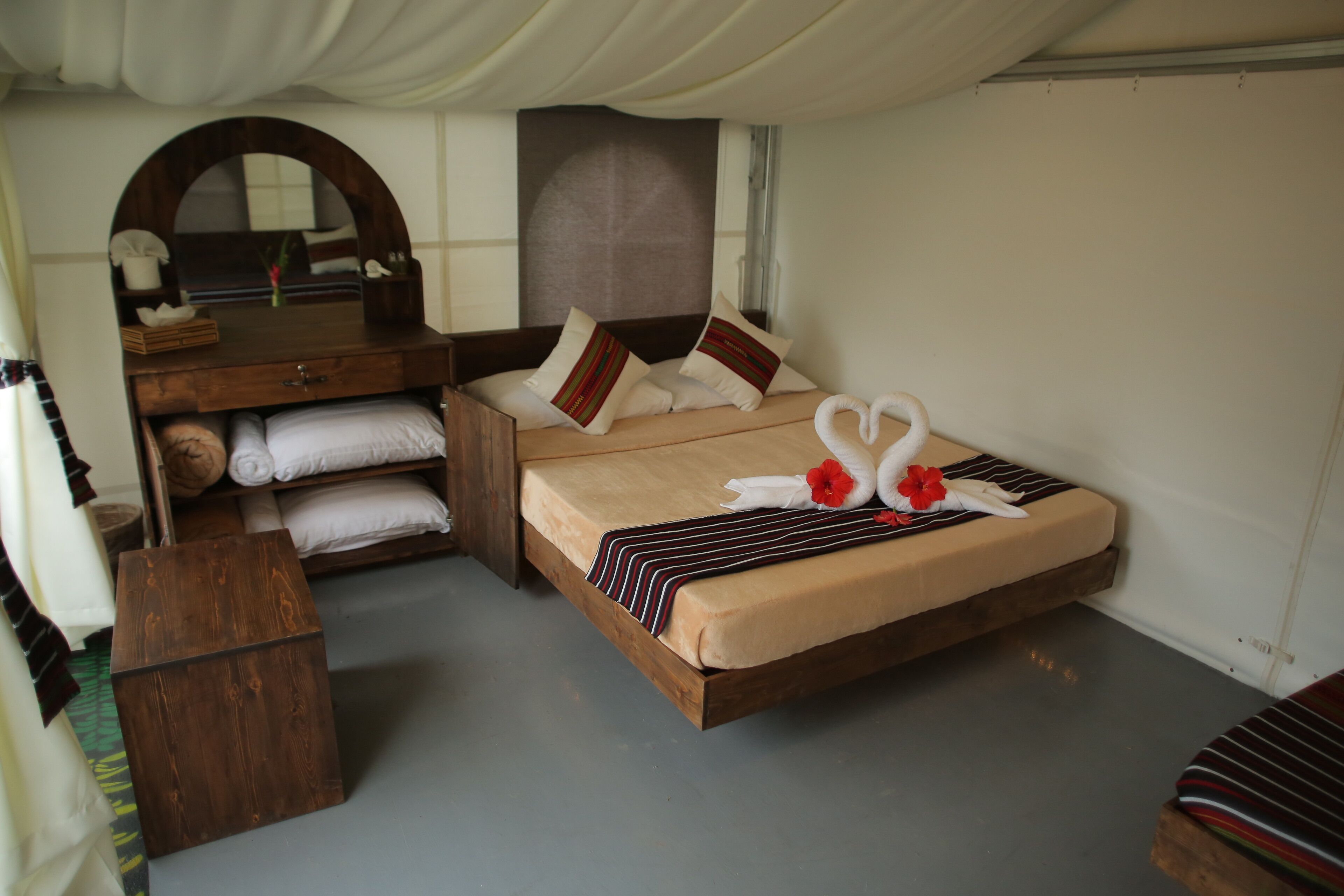Un dormitorio con una cama y cómoda de madera, un espejo y un banco.