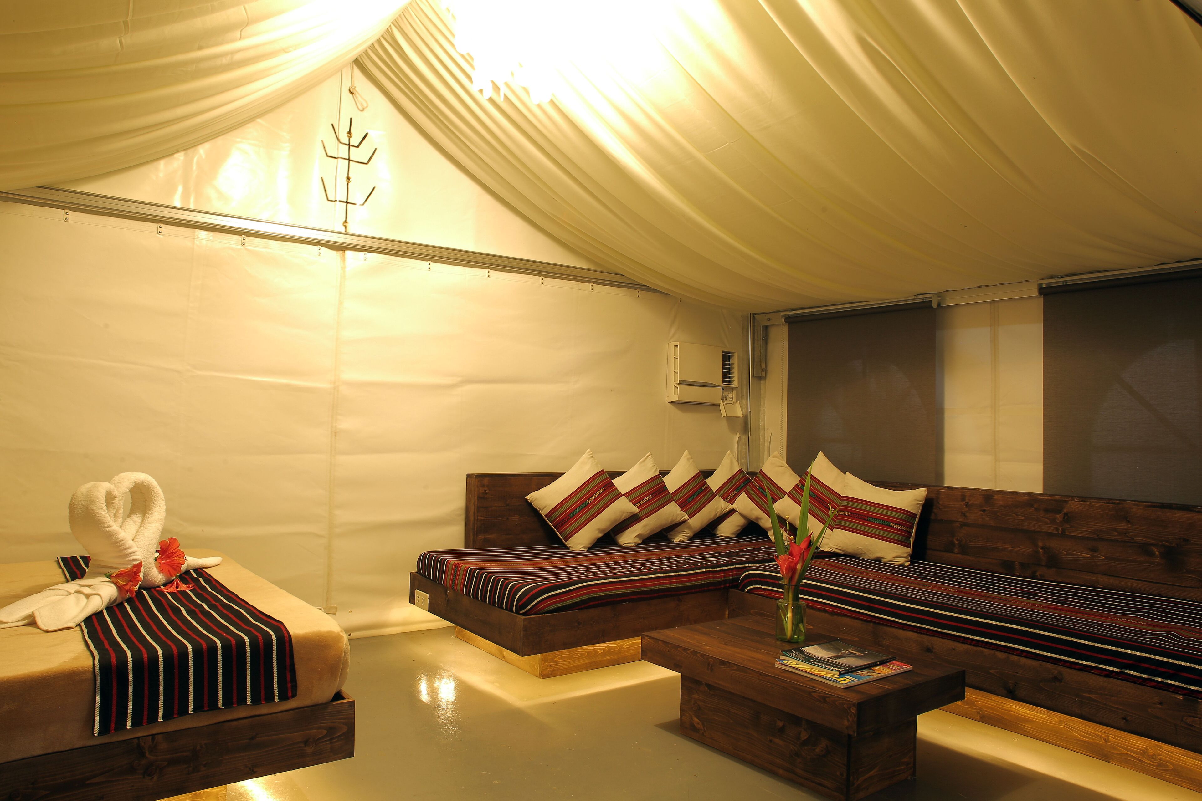 A cozy room with a sofa, a small table, and a bench. There is a heart-shaped towel and a red flower on the bench.