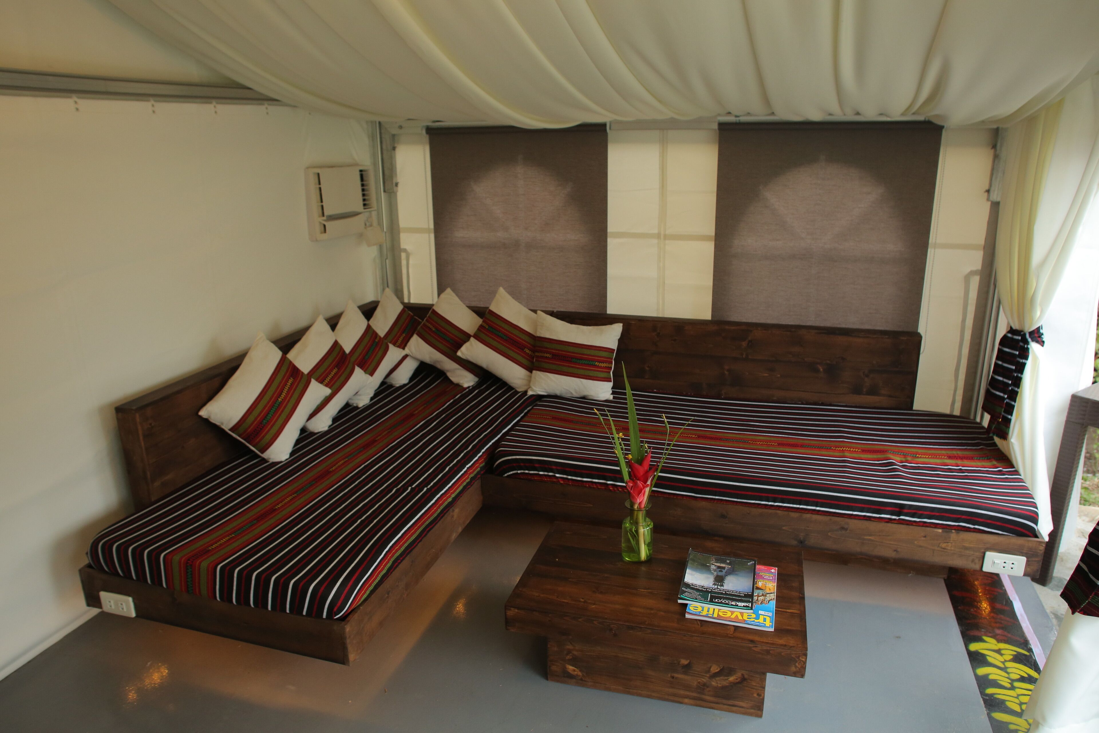 A cozy room with a wooden sofa set, a small coffee table, and a window with curtains.