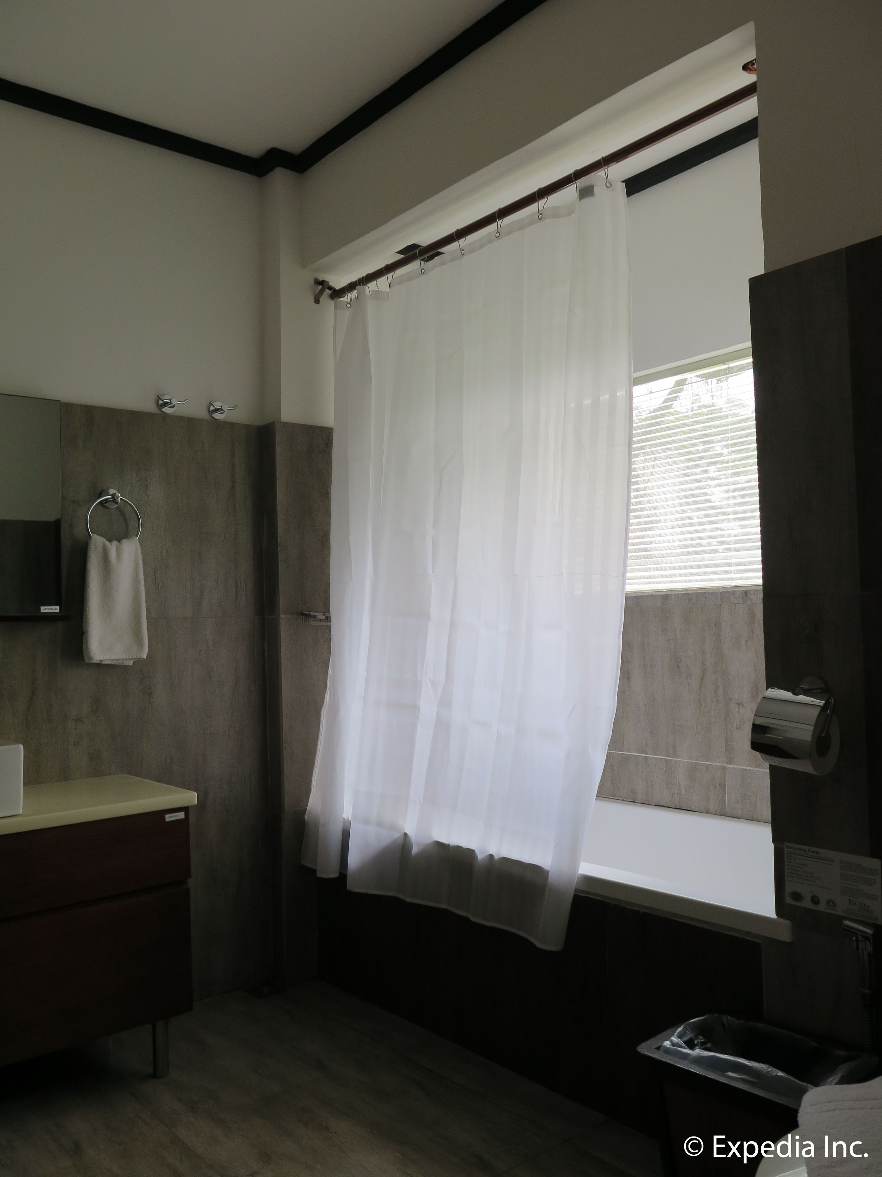 A bathroom with a wooden vanity, a towel ring, a toilet paper holder, and a window with blinds.