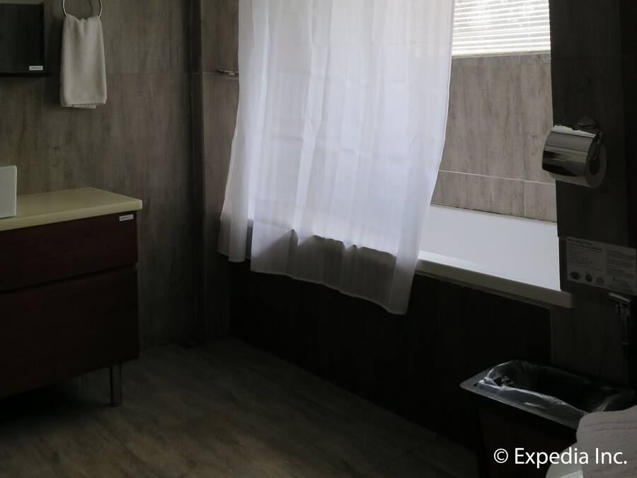 A bathroom with a wooden vanity, a towel ring, a toilet paper holder, and a window with blinds.