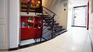 A modern interior with a staircase leading to a red area, possibly a lobby or service area, and a door at the end of the hallway. - Wifala Thematic Hotel (Cusco)
