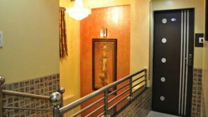 A staircase with a metal railing, a wooden door with a number, and a wall-mounted light fixture. - Hotel Planet Plaza (Mumbai)