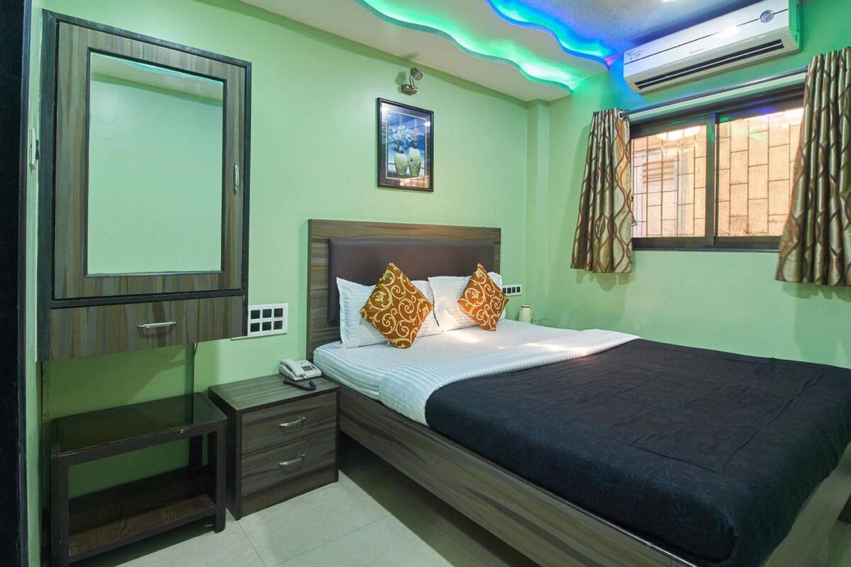 A bedroom with a bed, bedside table, and an air conditioning unit.