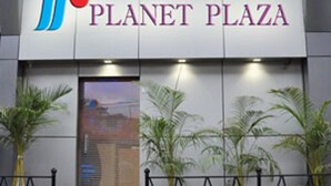 The exterior of Planet Plaza with a modern facade, a prominent logo, and potted plants in front. - Hotel Planet Plaza (Mumbai)