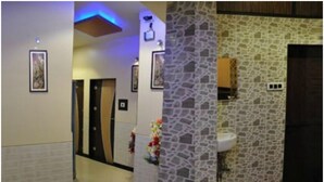 A hallway with a stone wall, a white sink, and a door. - Hotel Planet Plaza (Mumbai)