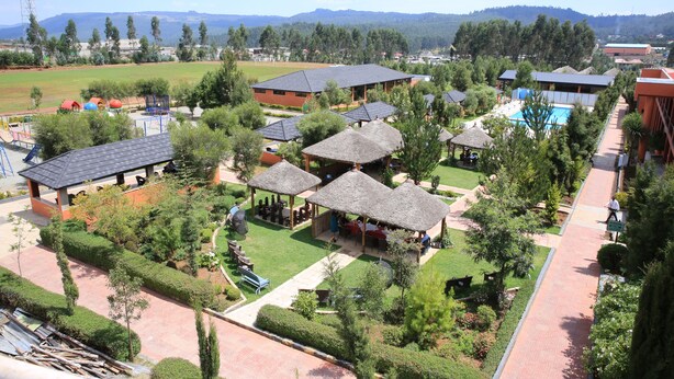 An aerial view of a resort with multiple buildings, a swimming pool, and well-maintained gardens. - Yaya Africa Athletics Village (Sululta)