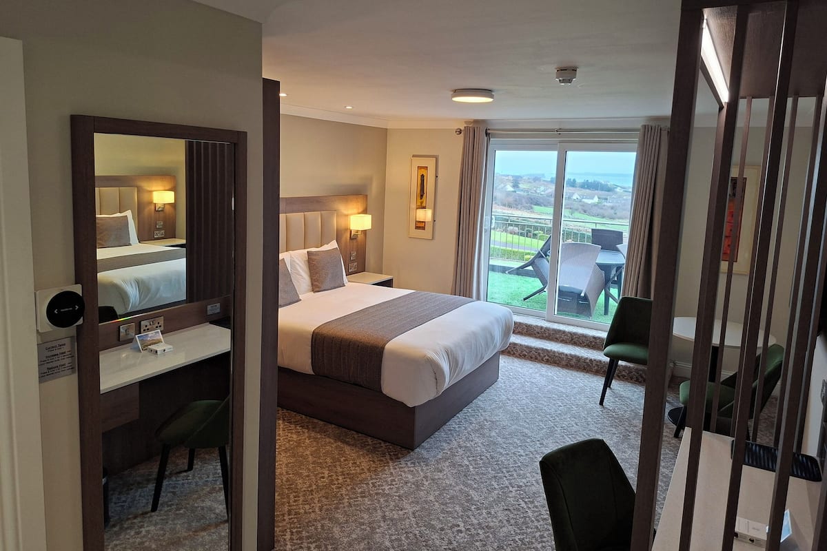 Une chambre d’hôtel avec un grand lit, un bureau, une chaise et une vue sur l’extérieur.