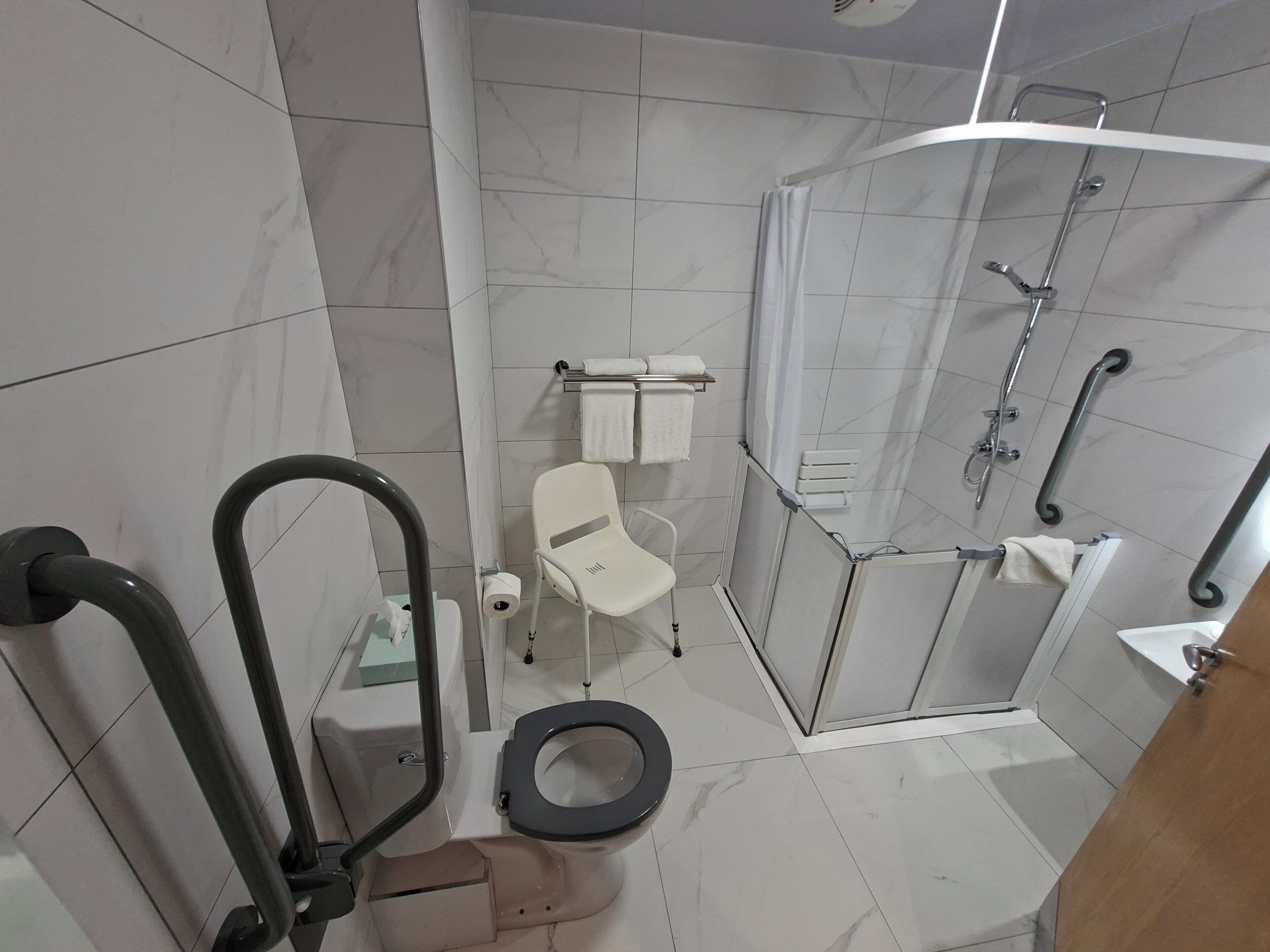 A bathroom with a toilet, a shower with a glass door, and a white sink.
