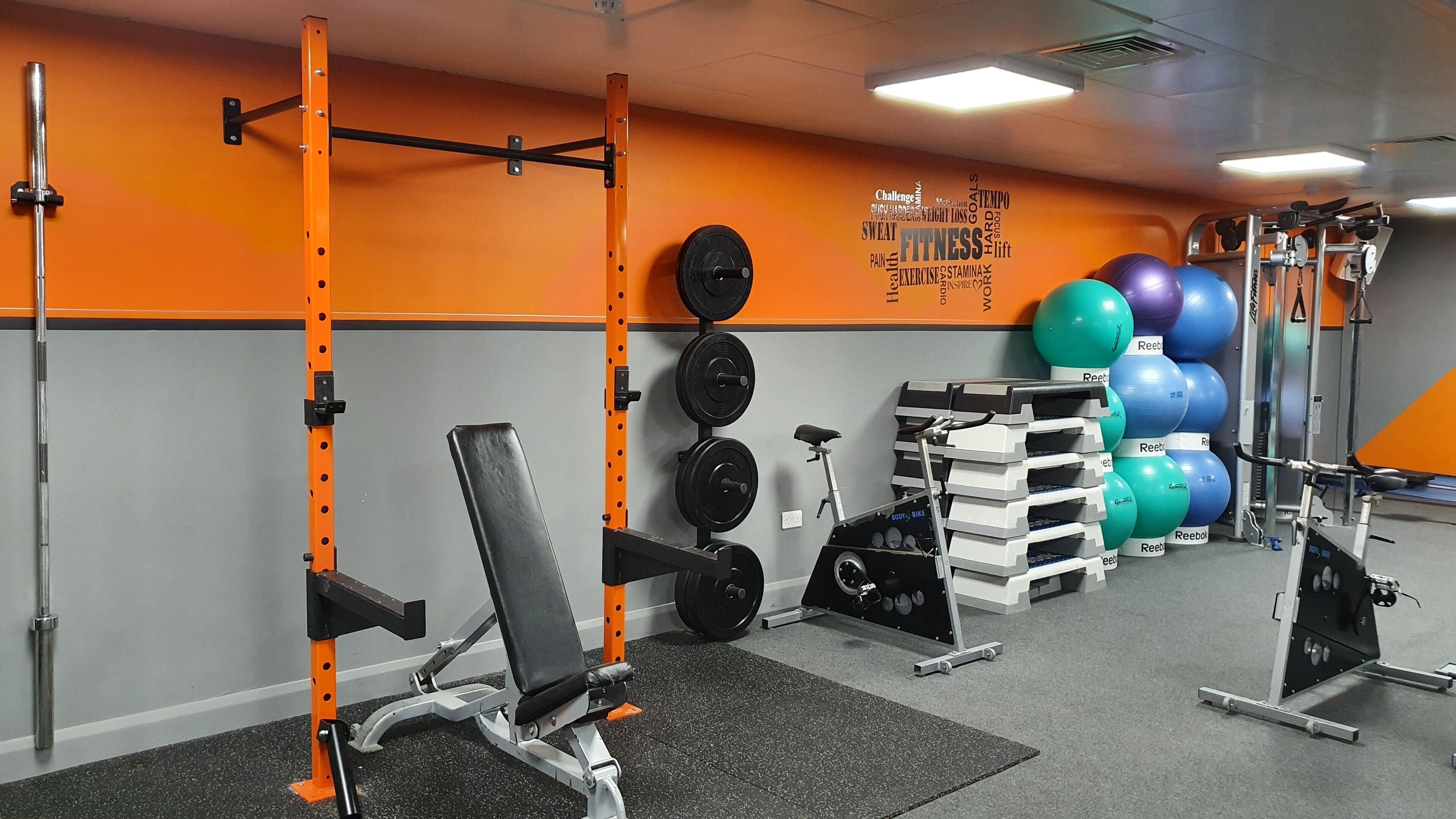 A gym with weightlifting equipment, exercise balls, and a stationary bike.